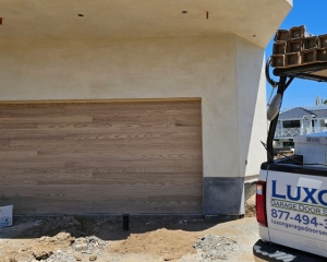 Steel garage door with natural oak wood look overlay installed on a new construction home in Seal Beach, CA