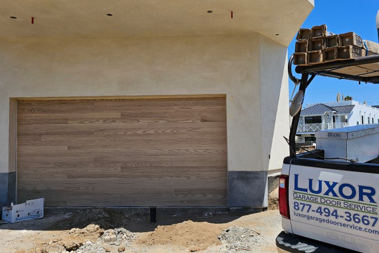 Steel garage door with natural oak wood look overlay installed on a new construction home in Seal Beach, CA